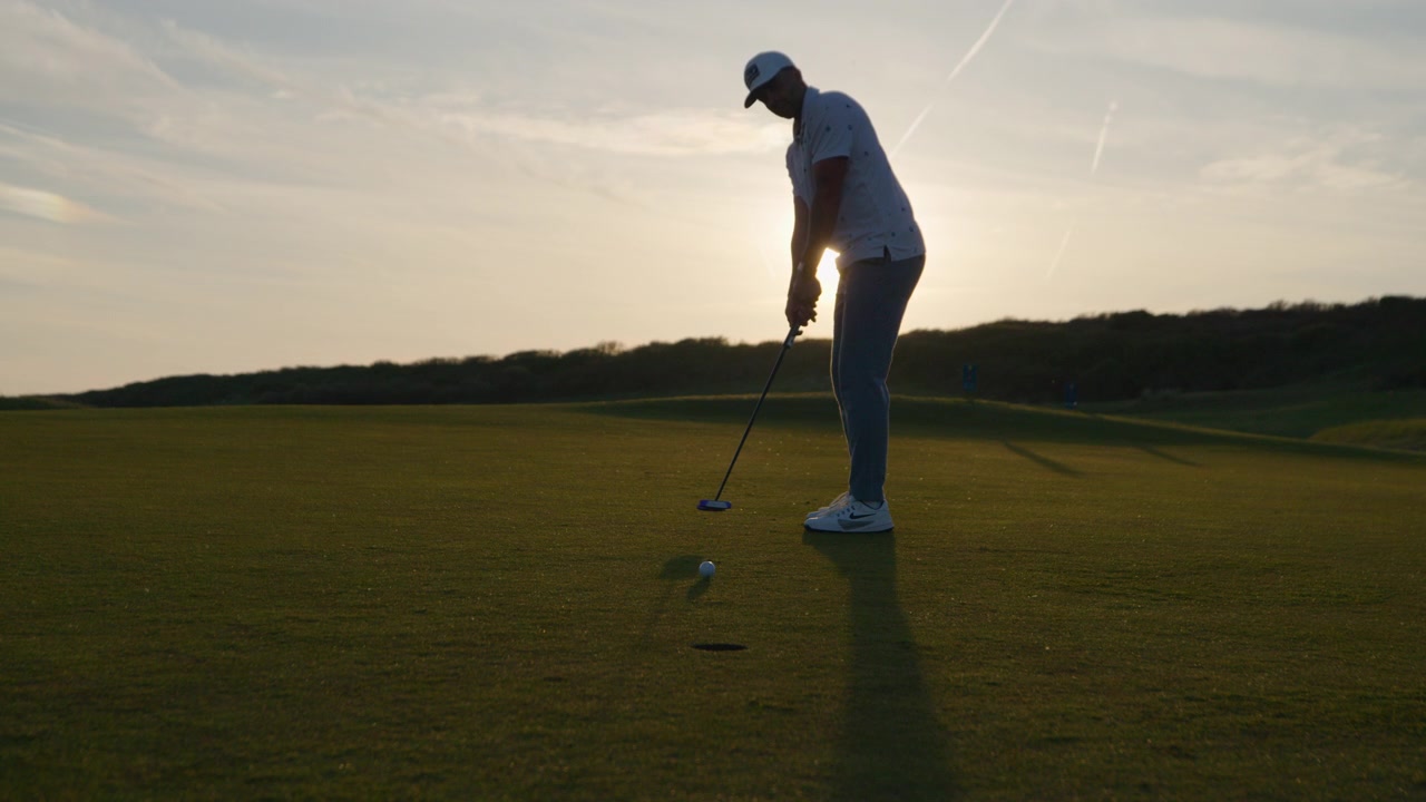 Golfista imbuca la pallina da golf in buca sul green - Slow motion all'ora d'oro