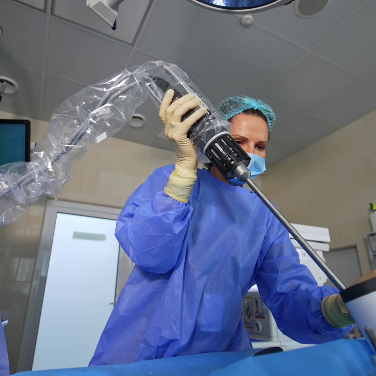 Female doctor disconnects the part of robotic arm and puts it into special vessel. Da Vinci robot surgeon working at operational room. Low angle view