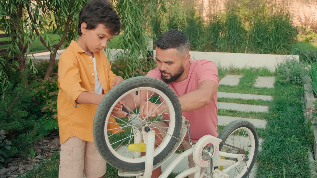 Father And Son Fixing Bicycle Wheel Outdoors