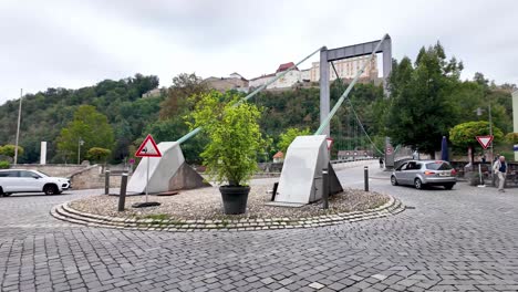 walking on cobbled street with the view over to pedestrian bridge and castle on the hill, passau in germany. runner, cyclists and cars with a corner restaurant