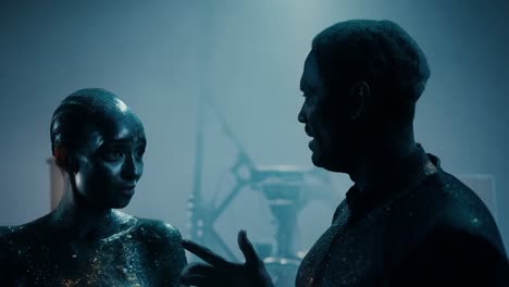 featuring a cinematic dialogue between two futuristic characters covered in metallic paint, creating an otherworldly ambiance on set