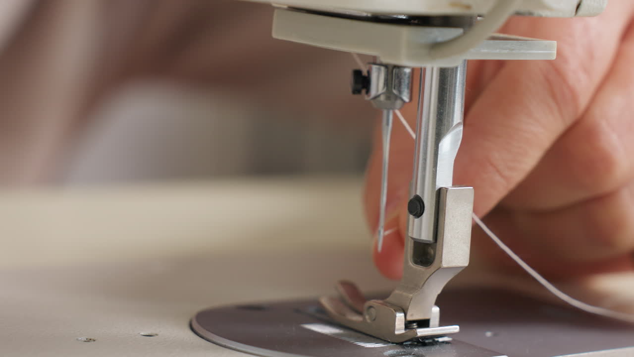 Thread passing through needle on sewing machine, focusing on precision, mechanical detail, minimal workspace, highlighting tension, skillful handling, and gentle motion for accurate stitching
