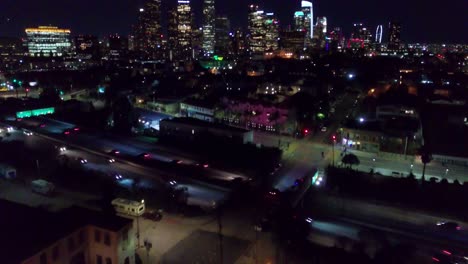 aerial tilt up from traffic on highway to reveal downtown los angeles skyline at night