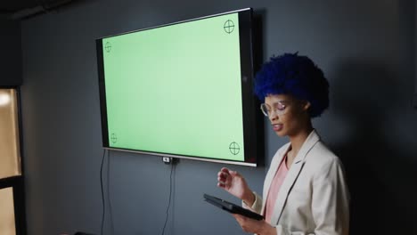 mujer de negocios casual biracial haciendo una presentación con una tableta en la oficina, espacio de copia, cámara lenta