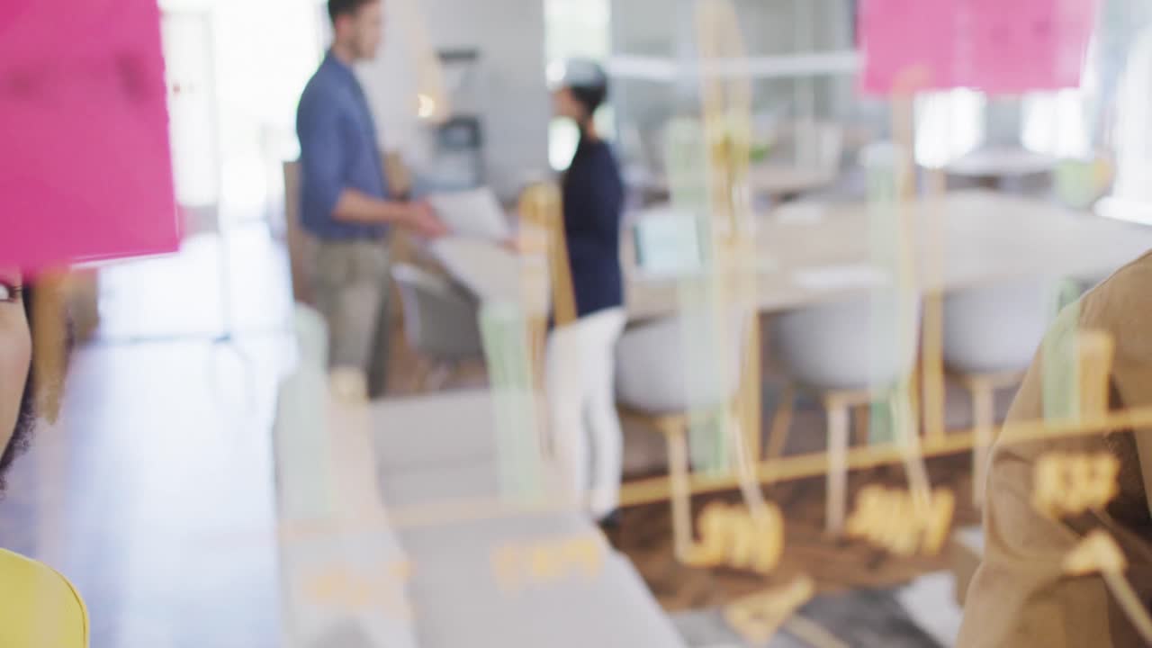 다양한 사업가들이 유리 블랙보드에 글을 쓰고 사무실에서 브레인스토밍을 하고 있습니다.