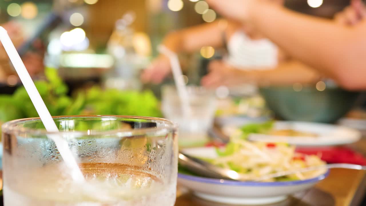 Diners enjoy a lively meal in a bustling Bangkok restaurant. Warm lighting and blurred motion create an energetic atmosphere