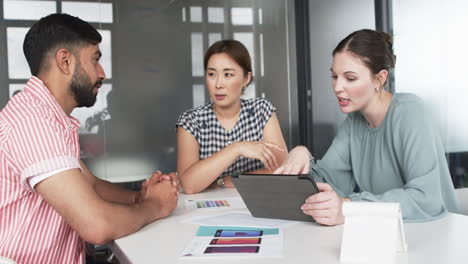 Diverse-group-of-business-professionals-engaged-in-a-discussion-with-a-tablet