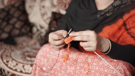 las manos de la mujer tejen con agujas artesanales e hilo rojo y negro