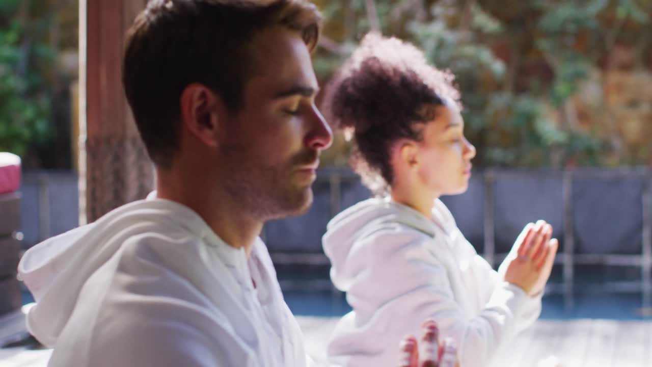 혼성 인종 부부 가 휴가 집 에서 요가 를 연습 하고 함께 명상 하고 있다