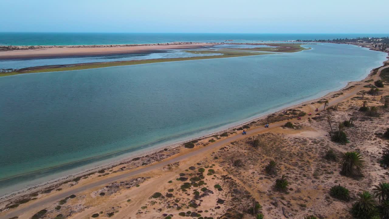 An aerial view of a beach, with the ocean and sandy shoreline visible in the Lagoon of Djerba at Tunisia , ATV quad on A dirt pathway that crosses through the area