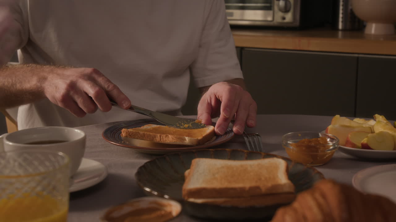 Man Spreading Jam on Toast at Breakfast