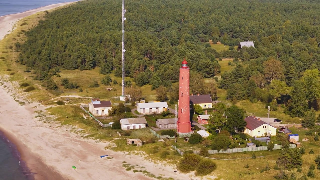Majakkatornimaisema ja vartiotornirakennus vihreällä metsäisellä rannalla. Panoraamakuva dronella.
