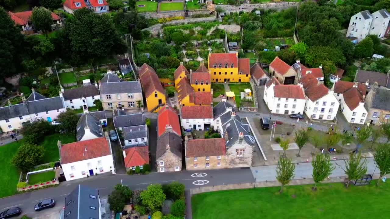 Aerial view of Culross in Fife, Scotland, featuring the ochre-yellow Culross Palace and surrounding historic houses with red-tiled roofs, a popular heritage and tourism destination