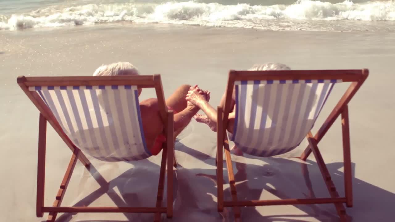 해변 의자 에서 손을 잡고 있는 평화로운 노인 부부