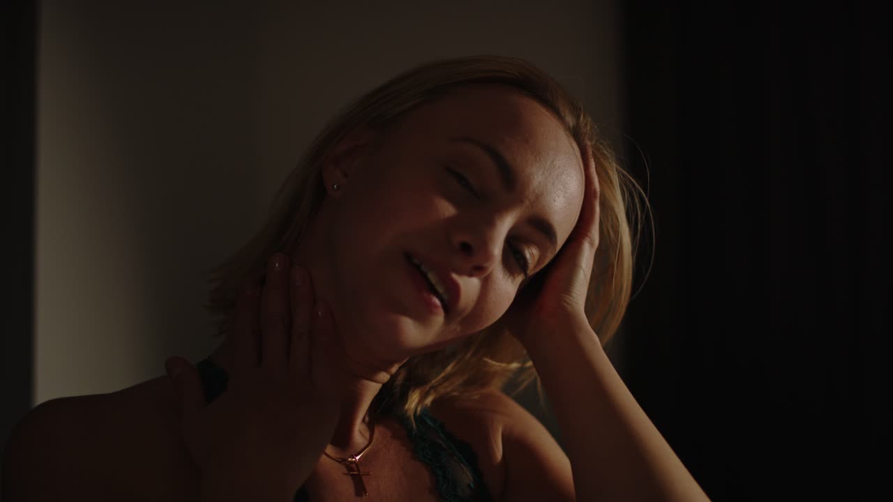 una mujer bonita vestida con lencería juega sensualmente con su cabello y mira tentadoramente a la cámara