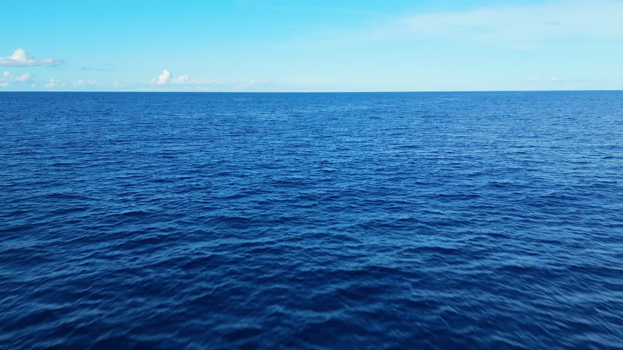 Aerial view of ocean with a vast blue surface, creating a tranquil and meditative background, push in and tilt up