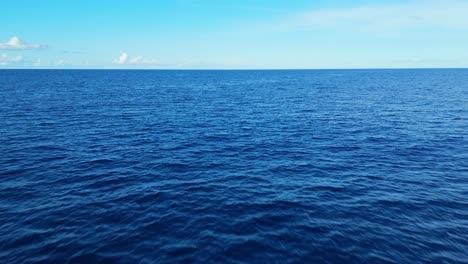 aerial view of ocean with a vast blue surface, creating a tranquil and meditative background, push in and tilt up