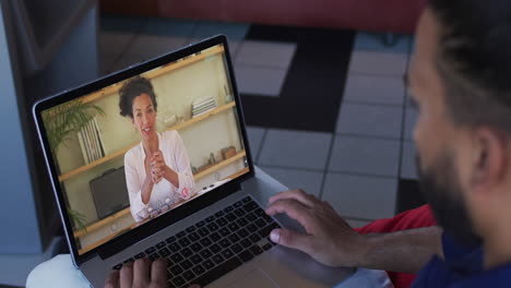 hombre de oriente medio haciendo una videollamada con una colega de oficina en una computadora portátil