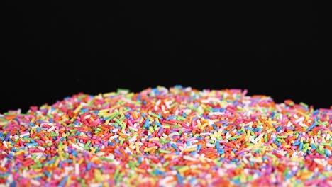 rainbow sprinkles cascade against a black background