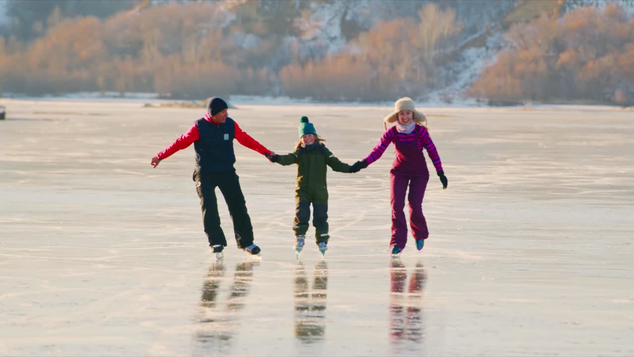 Familie skøjter på en frossen sø om vinteren