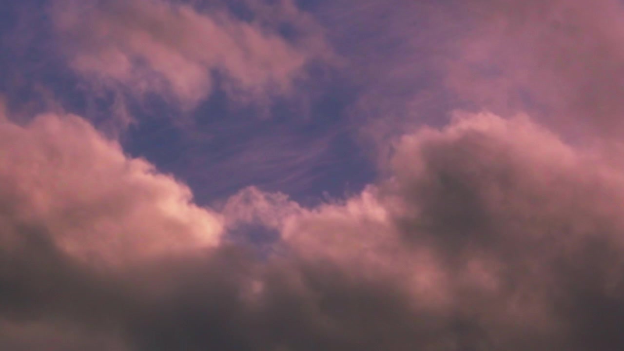 Time Lapse of Swirling Dark Clouds Passing Quickly with Red Tones and Blue Sky in Background