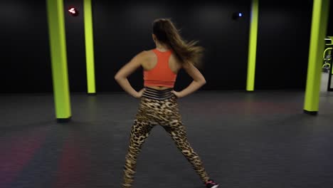 a fit young woman jumping sideways as part of a cardio excercise routine at a gym