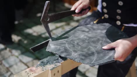 a close up video of a man carving an owl in the rock in a german festival from the middle ages called "wallenstein