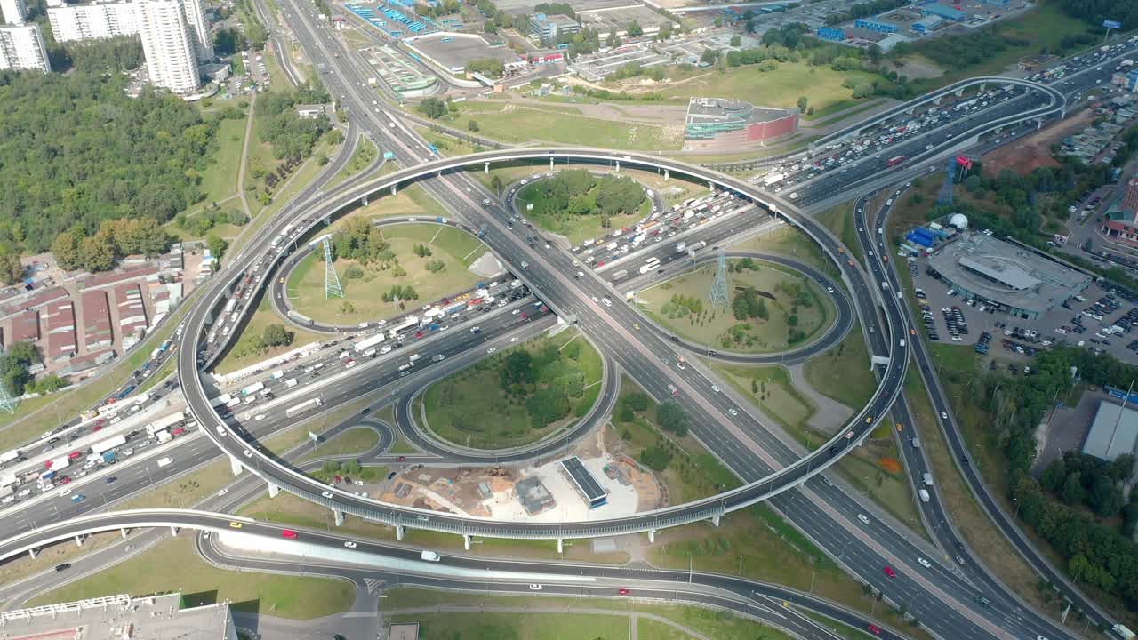video timelapse de atasco de tráfico en grandes intersecciones y pasos elevados con salidas de trébol. vista aérea de arriba hacia abajo desde un avión no tripulado. concepto de vida cotidiana de la gran ciudad. movimiento de alta velocidad. nubes y sombras vienen en lugar del sol. naturaleza y edificios a su alrededor.