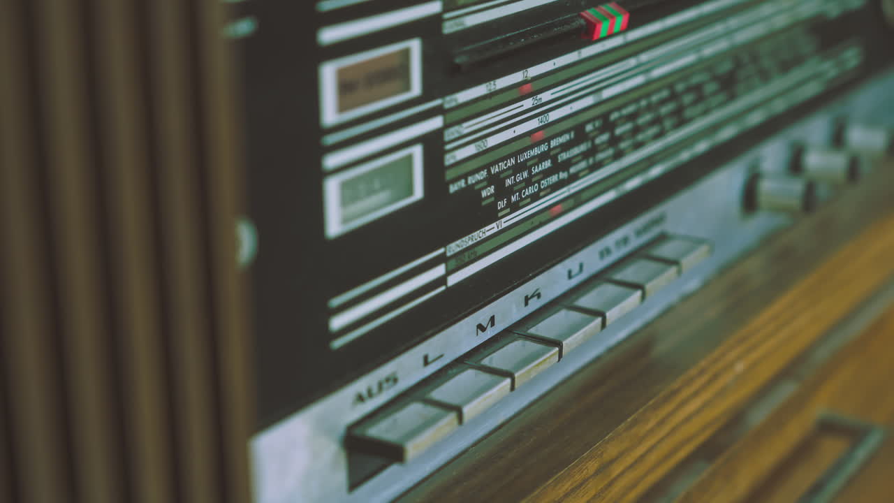 Close-up of hand operating push switches on vintage radiogram radio player. Suitable for retro electronics, broadcasting equipment and audio technology visuals