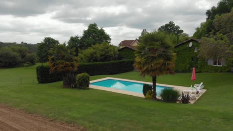 cinematic aerial revolve around private pool in french villa in the quiet countryside of france on overcast afternoon