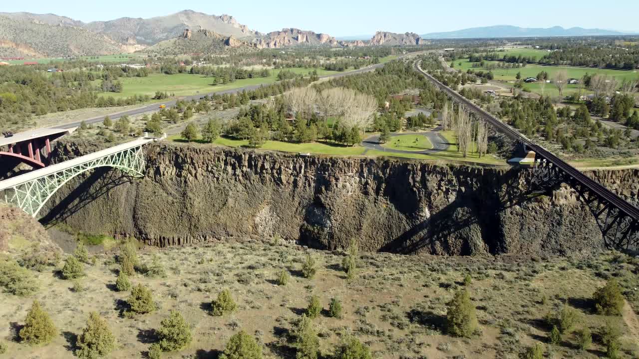 US, Oregon, Redmond, Crooked River High Bridge, 2025-04-12 - Drone view of the railroad, pedestrian, and road bridges over the Crooked River at Highway 26 in spring with Smith Rock in the distance.