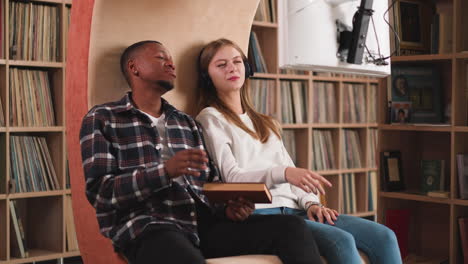 friends discuss movie seen in library. black man and blonde woman talk watching informative video in modern college library. place for self-development