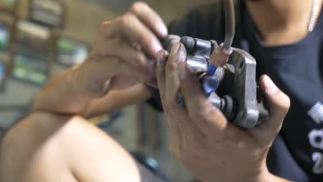 close-up footage of the technician working on motorcycle brake caliper cleaning process