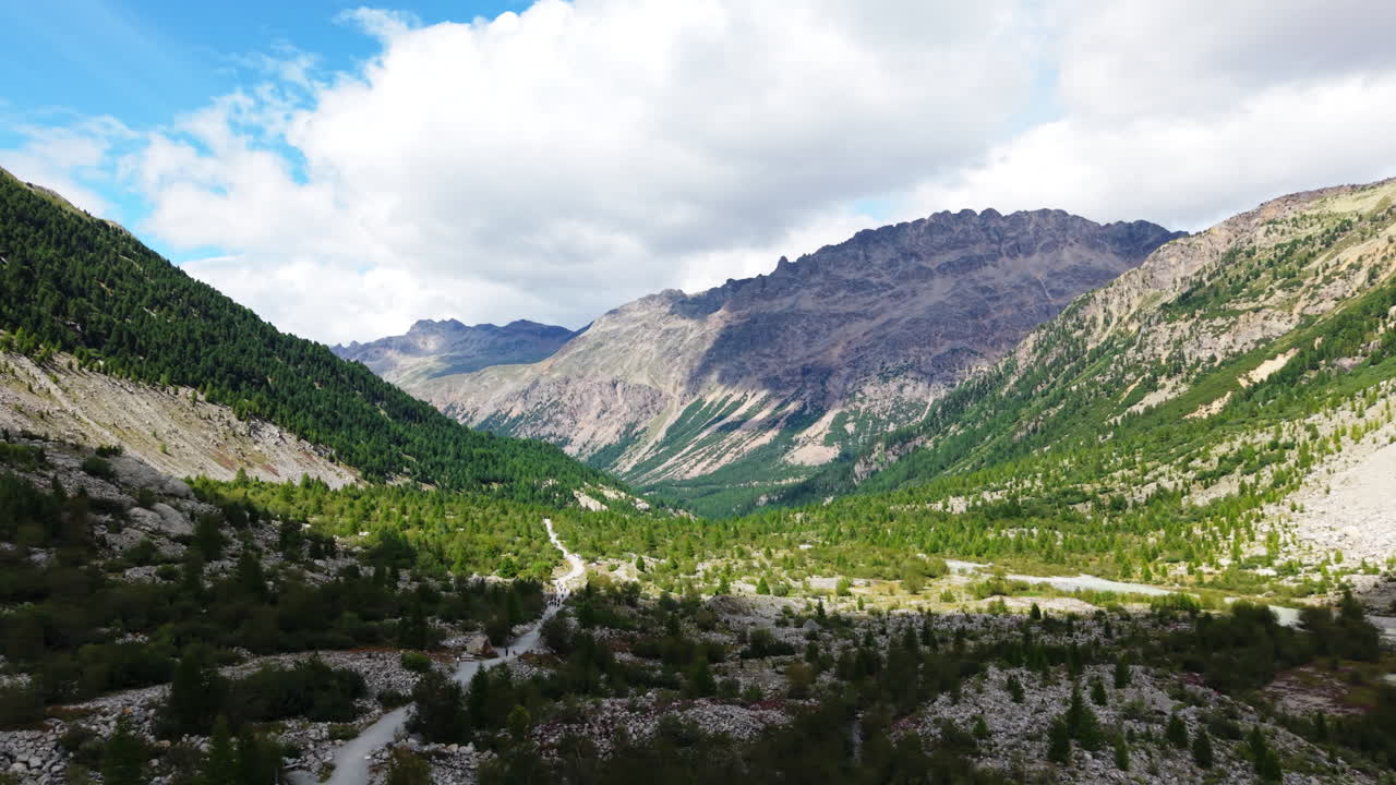 Ripresa aerea con drone sulla Val Morteratsch in Svizzera, che mostra la foresta illuminata dal sole, i pendii montani e il paesaggio glaciale