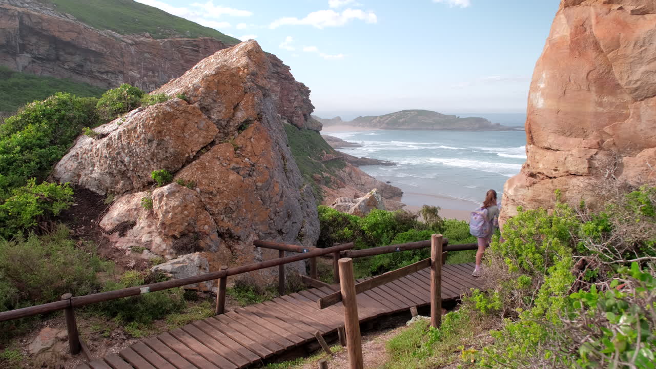 Mamá y sus hijas gemelas caminan por una pasarela de madera en el sendero de Robberg