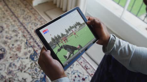 compuesto de un hombre sentado en casa, viendo un partido de hockey en la tableta