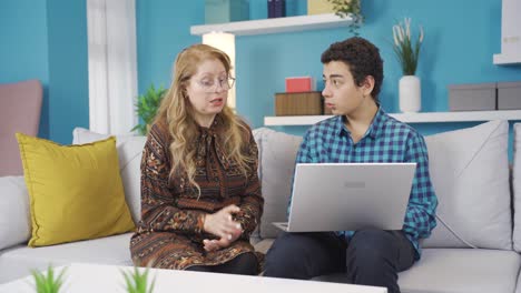 joven usando una computadora portátil con su madre en casa.
