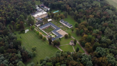 Fall-colors-dominate-the-beautiful-forest-surrounding-Castle-Bon-Repos-near-Prague,-aerial-orbit