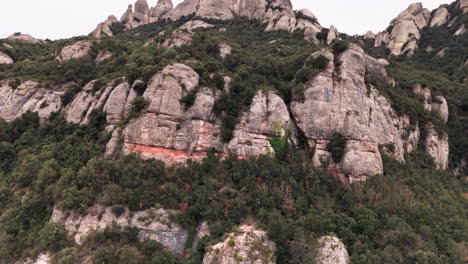 una toma de una grúa drone que revela con gracia los picos redondos de los acantilados de montserrat en el telón de fondo de un tranquilo día nublado