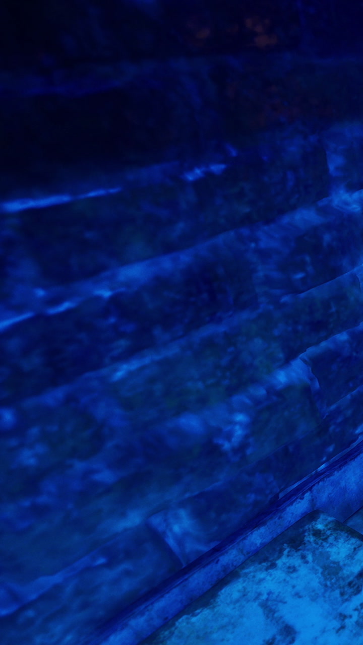 Water reflecting light against a stone wall in a dark space