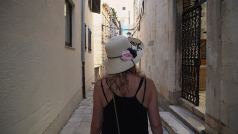 woman admiring the old buildings while walking in the paved alley. - rear view