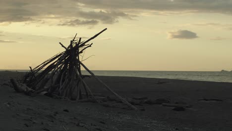 Silhouette-Einer-Holzpyramide-Für-Ein-Lagerfeuer-Am-Strand-Während-Des-Sonnenuntergangs