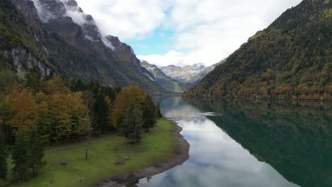 Klöntalersee-Glarus-Switzerland-left-to-right-pan-shot-of-a-lake-surrounded-by-thick-vegetation-and-tall-trees