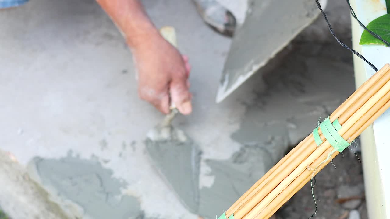 Worker skillfully smooths wet concrete with a trowel on a construction site. Close-up shots highlight precision and technique