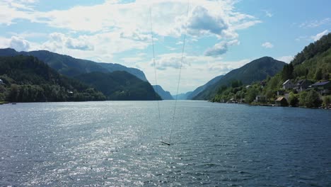 tall spectacular swing hanging in front of mighty norwegian fjord veafjord - amazing panoramic fjord view - sunny day backward moving aerial - veafjorden norway