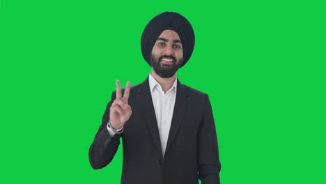 happy sikh indian businessman showing victory sign green screen