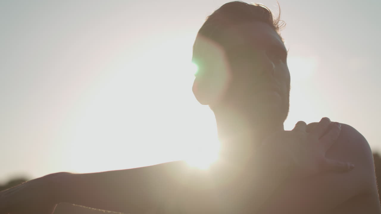 태양에 의해 등을 맞대고 있는 동안 운동하기 전에 공원에서 뻗어 있는 남자의 클로즈업 샷