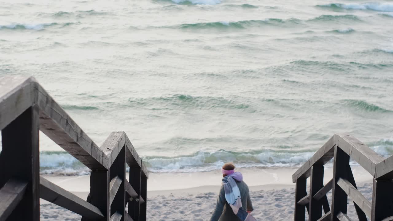 Woman walking down wooden stairs to the beach