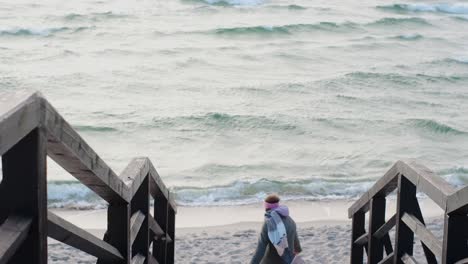 woman walking down wooden stairs to the beach