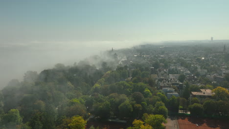 city of sopot surrounded by fog with green trees and rooftops visible through the mist